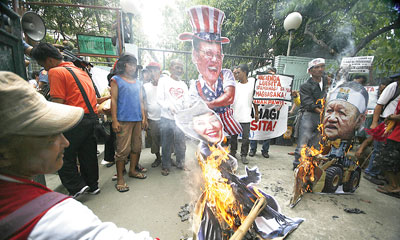 Hacienda Luisita farmers burn effigies of Kris Aquino and her uncle, Jose “Peping” Cojuangco, during a rally in front of the Department of Agrarian Reform building in Quezon City on Thursday. The farmers claimed that the hacienda owned by the family of President Benigno Aquino 3rd has yet to be distributed to farmer beneficiaries. photo by Miguel de Guzman 