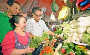 Department of Interior and Local Government Secretary Manuel ‘Mar’ Roxas 3rd (right) talks to a vegetable vendor during a visit at the Baguio City Public Market on Friday morning with Baguio Mayor  Mauricio Domogan (left). Roxas is in Baguio to announce a P2 billion anti-poverty fund for the Cordillera Region for the next two years.  PHOTO BY THOM PICANA