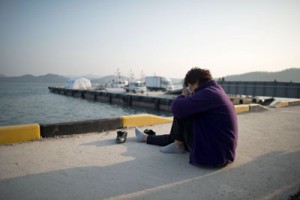 A relative weeps as she sits before the sea at an area where family members of victims of the South Korean ferry ‘Sewol’ are gathered, at Jindo harbor on Monday. AFP PHOTO