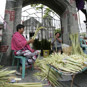 Vendors weave palm fronds in front of a church in Bacoor, Cavite, on Saturday. PHOTO BY RENE DILAN