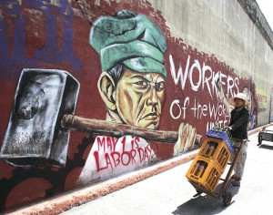 A worker walks past a mural on a street in Sta. Mesa, Manila, on Wednesday. Thousands of workers will hold rallies in Metro Manila and other parts of the country today to mark Labor Day. PHOTO BY RENE DILAN