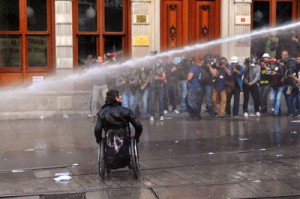 Photographers takes pictures of a man in a wheelchair as Turkish riot police use water cannons to disperse protesters who staged a demonstration on Istiklal avenue in Istanbul, in memory of the victims of the Soma mine explosion. AFP PHOTO