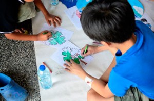 A kid colors a picture that illustrates trees are a source of clean air