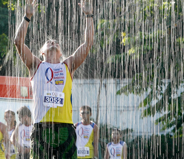 A participant to the Tulong na, Tabang, Tayo na Takbo na fun run pauses under water sprinklers set up in Taguig City. The event, sponsored by DZMM, aimed to collect funds for victims of typhoon Yolanda. PHOTO BY MIGUEL DE GUZMAN