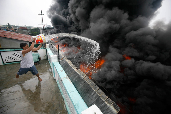 A bucket of water fails to douse a fire that engulfed a warehouse in Valenzuela City where scrap plastic materials were stored on Wednesday. No one was reported hurt in the fire that raged for hours before it was placed under control. Photo By Miguel De Guzman 