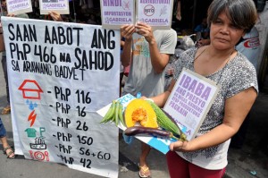 A member of the women’s group Gabriela holds placards and vegetables during a protest rally calling on the government to act on the rising prices of basic goods. The group claimed that of the P466 minimum wage in Metro Manila, a big chunk goes to housing rent, education and electricity and that only P42 is left for food.  Photo By Edwin Muli 