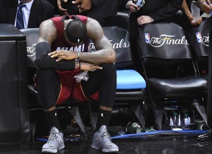 LeBron James of the Miami Heat sits on the sidelines after cramping up during Game 1 of the NBA Finals against the San Antonio Spurs, June 5, 2014 in San Antonio, Texas.  The Spurs defeated the Heat 110-95, taking to lead the series 1-0.  AFP PHOTO / Robyn Beck