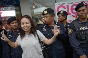 This file picture taken on Monday shows an anti-coup protester flashing a three-finger salute as she stands beside a line of policemen as a gathering at a shopping mall, which was broken up by security forces in downtown Bangkok. AFP PHOTO