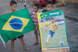 Children pose with a poster of Brazilian football player Neymar and a Brazilian flag during their decorating work on a street for the FIFA World Cup 2014 in Rio de Janeiro, Brazil on the eve of the opening of the event. AFP PHOTO