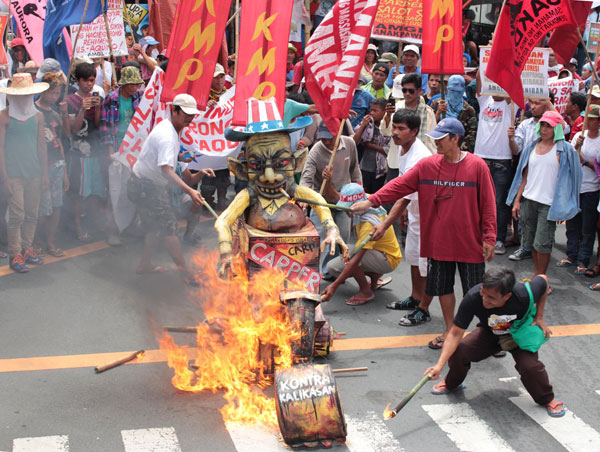 Members of farmers’ groups torch an effigy during a rally near President Benigno Aquino 3rd’s house on Times Street in Quezon City. The farmers said the Comprehensive Agrarian Reform Program that expires today failed to protect farmers from big landholders. PHOTO BY RUY MARTINEZ