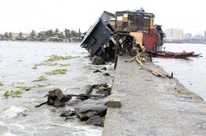 A man tries to fix the roof of what is left of his typhoon-battered house at the edge of the baseco coastal community in manila on thursday.  Photo by Rene H. Dilan