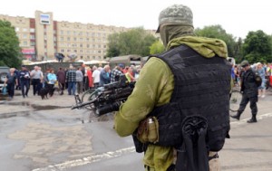 A Ukrainian serviceman stands guard as residents wait in line to receive food from employees of the Emergency Ministry near City Hall in the eastern Ukrainian city of Slavyansk on Monday. AFP PHOTO