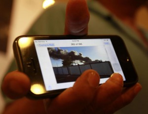  One of 41 Filipino workers who returned from Libya on Monday shows a photo he shot from his phone camera of a burning building in Tripoli at the height of the fighting between rival militias. PHOTO BY RENE DILAN 