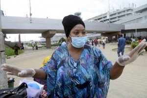 A woman wearing a protective face mask and gloves, speaks to a worker upon arrival at the Murtala Muhammed Airport in Lagos on Tuesday. Nigeria confirmed a new case of Ebola in the financial capital Lagos, bringing the total number of people in the country with the virus to 10. AFP PHOTO