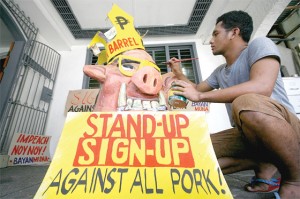 A member of a militant group prepares an effigy that they will use in their march today to denounce the pork barrel system. Photo by Miguel de Guzman