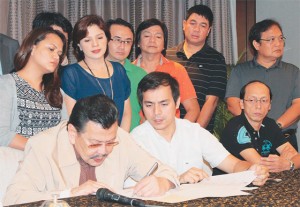 Mayor Joseph Estrada signs an order lifting the truck ban in Manila as Vice Mayor Isko Moreno (center, seated) and city councilors look on. PHOTO BY RUY MARTINEZ