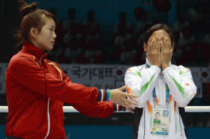 Bronze medalist Luu Thi Duyen (left) of Vietnam urges India’s Laishram Sarita Devi to go on to the podium on Wednesday after she decided to refuse to accept her bronze medal during the women’s lightweight (57-60kg) boxing awards ceremony during the 17th Asian Games in Incheon. AFP PHOTO