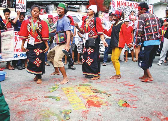 Their feet smeared with red dye, symbolizing the blood of 83 civilians killed during military operations, members of a tribe from Mindanao perform a dance during a protest demonstration on Wednesday at a gate in Camp Aguinaldo.  PHOTO BY MIKE DE JUA