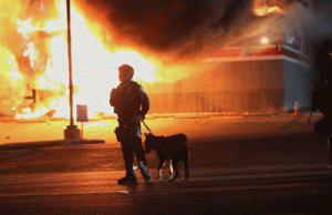 VIOLENCE A police officer watches as a building burns after it was set on fire during rioting following the grand jury announcement in the Michael Brown case on Tuesday in Ferguson, Missouri. AFP PHOTO