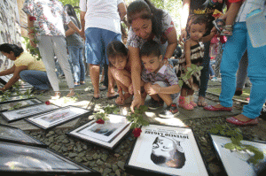 DESAPARECIDOS Families and relatives of victims of enforced and involuntary disappearances offer flowers and prayers on the photographs of their missing kin during a short ceremony at the Bantayog ng mga Bayani Memorial Center in Quezon City on All Souls’ Day, Sunday. PHOTO BY MIGUEL DE GUZMAN