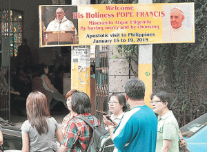 VIP VISITOR  Churchgoers gather near a billboard proclaiming Pope Francis’ visit next year outside the San Lorenzo Ruiz Church in Binondo, Manila. The Catholic church recently bared the Pope’s activities in the Philippines, which include dining with typhoon victims and masses at the Manila Cathedral and University of Santo Tomas. PHOTO BY EDWIN MULI