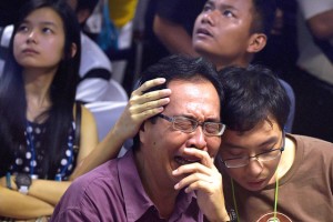 Family members of passengers onboard the missing Malaysian air carrier AirAsia flight QZ8501 burst into tears after watching news reports showing an unidentified body floating in the Java sea inside the crisis-center set up at Juanda International Airport in Surabaya. AFP photo