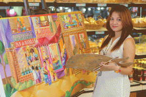 The artist and her ‘Makulay, Makabuluhan at Makasaysayan ang Pasko sa Pan de Manila’ tapestry, whose vivid scenes are featured in various Christmas packagings
