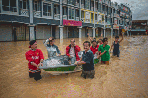 FLOODED TOWN  Local residents use a boat to cross floodw aters in Kota Bahru on Sunday. AFP PHOTO