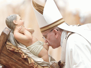 CHRISTMAS MASS  The Pope kisses the unveiled baby Jesus during a Christmas Eve Mass at St. Peter’s Basilica on December 24 at the Vatican. AFP PHOTO