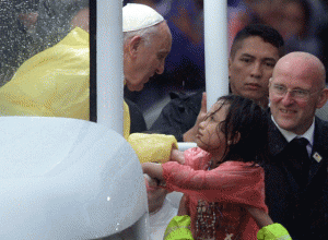 Pope Francis talks to a child drenched by the rain after celebrating mass. AFP PHOTO