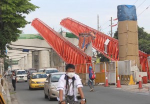 CAUSE OF DELAY  Motorists pass the broken girder launcher that broke and fell on five vehicles late Monday. Because of the accident, officials fear that the completion of the NAI Skyway project will be delayed. PHOTO BY RUY L. MARTINEZ