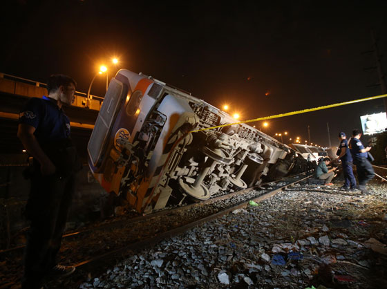 Policemen secure the Philippine National Railway train that jumped out of its tracks near the Magallanes Interchange in Makati City on Wednesday. At least 80 passengers were injured according to the police. 