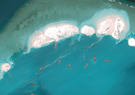 This handout photo taken on March 17, 2015 by satellite imagery provider DigitalGlobe and released to AFP by the Asia Maritime Transparency Initiative department at the Center for Strategic and International Studies (CSSI) think tank shows a satellite image of vessels purportedly dredging sand at Mischief Reef in the Spratly Islands in the disputed West Philippine Sea. The series of satellite images posted on the website of the Center for Strategic and International Studies show a flotilla of Chinese vessels dredging sand onto Mischief Reef and the resulting land spreading in size. Beijing on April 9 reaffirmed its right to build on the disputed islands after the satellite imagery emerged of construction operations turning tropical reefs into concrete artificial islands.  The Philippines, Vietnam, Malaysia, Brunei and Taiwan all have overlapping claims in the area. AFP PHOTO