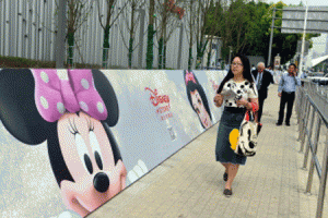 People walk past a banner of Disney animated characters outside China's first Disney flagship store at the Lujiazui financial district in Shanghai on May 20. US entertainment titan Disney opened its first Chinese store on May 20 ahead of its first mainland theme park launching, as it seeks to sell Mickey Mouse and friends to the Asian giant's middle classes. AFP PHOTO