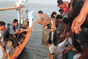 HELPING HAND Acehnese fishermen (left) help transfer Rohingya migrants (right) from their boat off the coast near the city of Geulumpang in Indonesia’s East Aceh district of Aceh province on Wednesday. AFP PHOTO