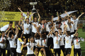 Sepahan FC captain Moharram Navidkia (C) holds the trophy as his teammates celebrate after becoming Iran's Premier League champions, after beating Saipa at the Foolad Shahr stadium in Isfahan on May 15, 2015, as their rival Tractor Sazi ended in a 3-3 draw against Naft in Tabriz. When the final whistle blew for Tractor Sazi and Naft match in Tabriz thousands of jubilant fans ran on to the pitch to celebrate what they thought was their team's first ever Iranian Premier League title but while the smiles were still wide and Portuguese coach Toni Oliveira was being hugged by supporters, the celebrations suddenly turned sour as it emerged that they had not won at all. AFP PHOTO