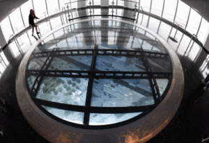 A member of the media stands on the Sky Portal, a 14-foot wide disc that delivers high-def footage from the street below at the One World Observatory May 20, 2015 during a media tour and preview in New York. This early visit to the Observatory at One World Trade Center will showcase all of the main attractions that the Observatory offers on floors 100 to 102 -- Voices, Foundations, Sky Portal, City Pulse and more. One World Observatory announced that its official public opening date will be May 29, 2015. AFP PHOTO 