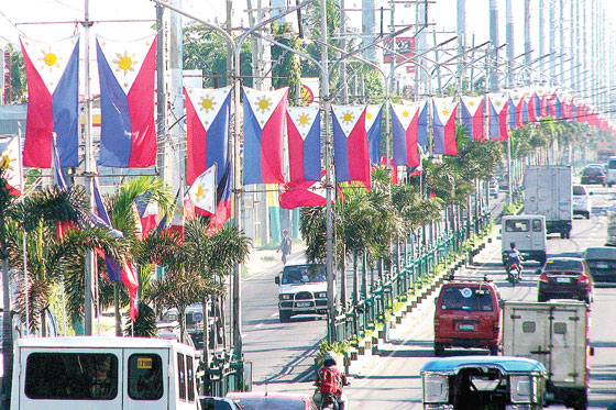 Dozens of Philippine flags adorn the stretch of Aguinaldo Highway in Dasmarinas City in Cavite. The country marks its 117th
