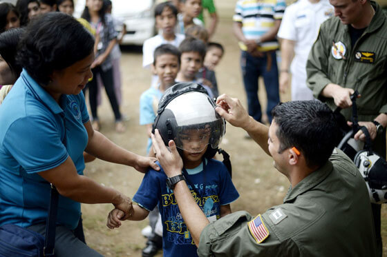 A boy nervously gazes at the camera as a US Navy serviceman fixes the helmet He was made to wear before boarding a P-3 Orion surveillance aircraft at the Antonio Bautista Airbase in Puerto Princesa City, Palawan. AFP PHOTO 