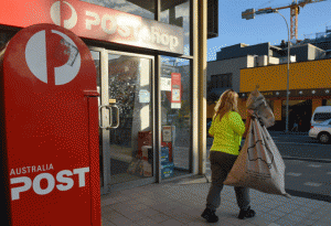 A worker carries a sack of letters after emptying a post box outside an Australia Post office in Sydney on Friday. Australia Post was expected to axe hundreds of jobs as it struggles with growing losses from a decline in letter volumes despite growth in its parcels business. AFP PHOTO