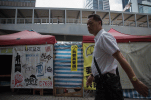 HONG KONG PROTESTS In a picture taken on June 13, 2015, a man walks past tents setup by pro-democracy protesters on a sidewalk outside the government headquarters in Hong Kong. Pro-democracy campaigners will take to the streets of Hong Kong on June 14 ahead of a vote on the political reform package that has divided the city and sparked mass protests. AFP PHOTO