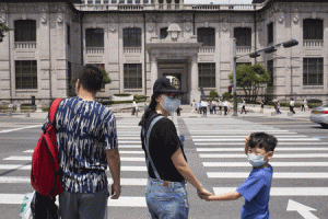 COSTLY OUTBREAK  A woman and a child wearing facemasks wait to cross a road before the Bank of Korea headquarters in Seoul on June 11, 2015. South Korea’s outbreak of the potentially deadly MERS virus forced the central bank to cut its key interest rate to ward off greater economic damage, as retailers report a slump in business. AFP PHOTO