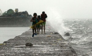 SPLASH BROTHERS Children run as waves buffeted by tropical storm Egay crashes into the breakwater in Malabon City. PHOTO BY MIGUEL DE GUZMAN