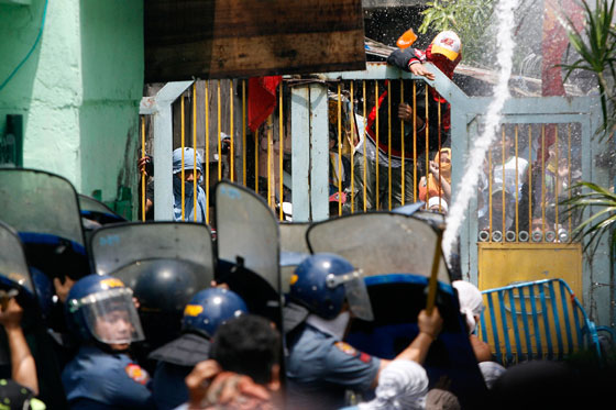 Police use shields to protect themselves from bottles, human waste and acid thrown at them by residents of  St. Benedict compound in Pasig City. At least 10 people were reported hurt in the incident on Monday. PHOTO BY MIGUEL DE GUZMAN 