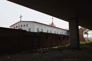 This photo taken on May 24, 2015 shows the “underground” Zhongxin Bridge Catholic Church below an expressway bridge in Tianjin. EachSunday hundreds pack the dilapidated building, some sitting on the floor or standing outside, straining to hear the bishop’s sermon over the rumble of passing trucks. AFP PHOTO 