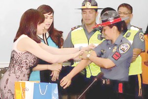 LOTION SOLUTION  Dr. Vicki Belo demonstrates to a female traffic constable how to apply a sunblock lotion that she donated to the PNP-Highway Patrol Group. PHOTO FROM PNP-PIO 