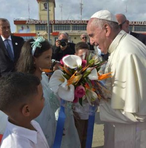 HOLA, PAPA  A handout picture released on September 22 by the Vatican press office, Osservatore Romano, shows Pope Francis (R) receiving a gift from a child upon his arrival at Antonio Maceo international airport in Santiago de Cuba. Santiago, the last stop on Pope Francis’s Cuban tour, is known for its revolutionary history, its rum and the troubadours who have infused the Caribbean island’s music with their tropical beats. AFP PH