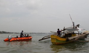 Coast guard personnel aboard a rubber speed boat check a motorized outrigger as they patrol the seas near Davao City and Samal island during the search for kidnapped foreigners. AFP Photo