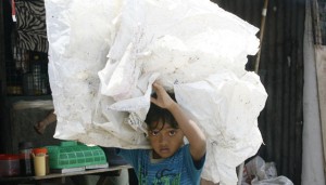 SUFFER THE CHILDREN A boy carries a bundle of plastic bags at a slum area in payatas, Quezon city.. pHOTO By Miguel De Guzman