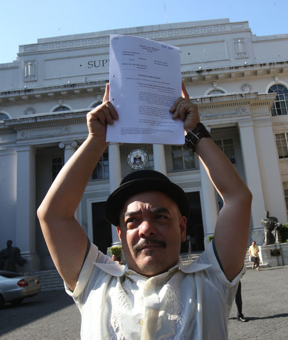 Heritage conservationist Carlos Celdran wears a derby hat as he holds aloft a copy of his appeal to the Supreme Court to have his conviction for disrupting a church service in 2010 overturned. The Manila Metropolitan Trial Court and Regional Trial Court found him guilty of offending religious feelings for barging into the Manila Cathedral dressed as national hero Jose Rizal and held up a placard with the word ‘Damaso’ before Catholic church officials in protest of the their opposition to the then reproductive health bill. ‘Damaso’ was a reference to the villainous friar from Rizal’s novel Noli Me Tangere. PHOTO BY RENE DILAN